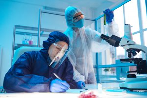Portrait of two scientists wearing biohazard gear while working on research in bio laboratory